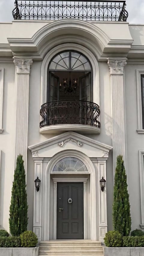 Villa entrance with tall pilasters, balcony railing and arched window