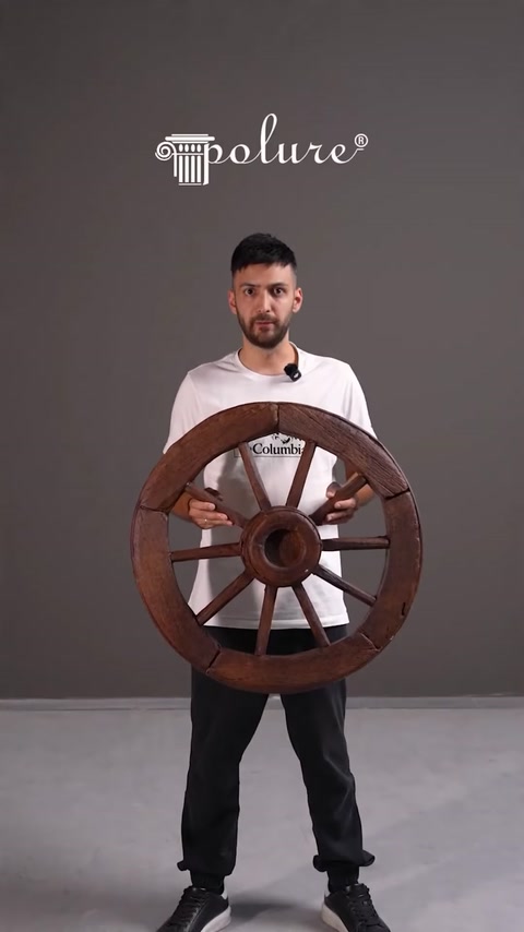Presenter holding a large decorative wooden-style wheel