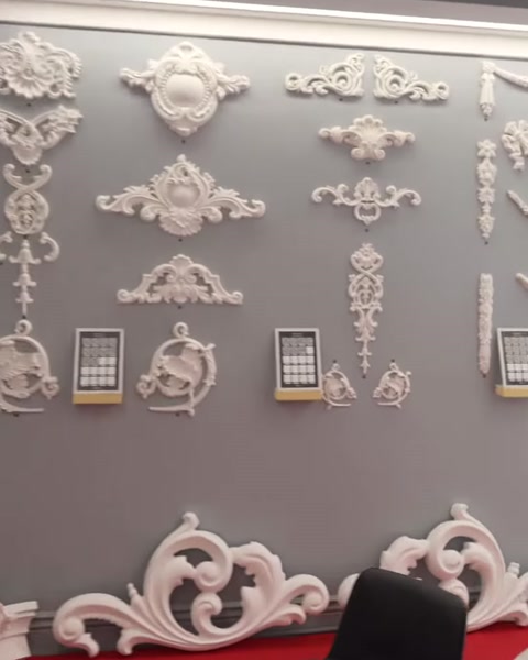 Diversi motivi decorativi bianchi sono esposti insieme su una parete espositiva