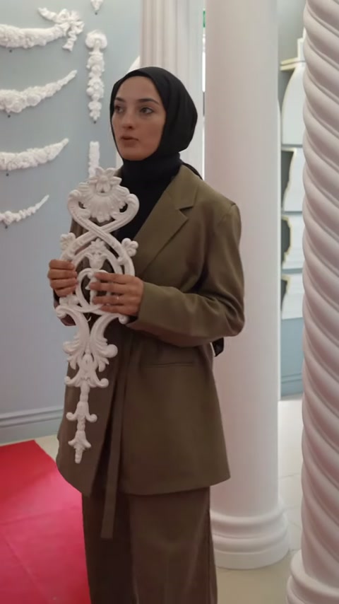 L'addetto tiene un motivo decorativo lungo e lavorato al petto davanti alla collezione di ornamenti murali