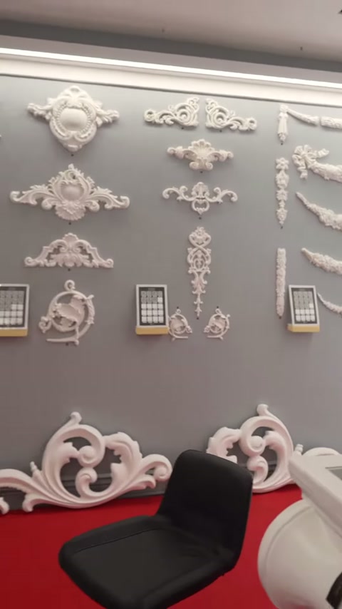 Una collezione di motivi classici è ordinatamente presentata sulla parete grigia della mostra