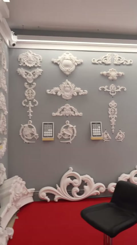 Sulla parete grigia sono visibili motivi con fiori, curve sinuose e forme angolari