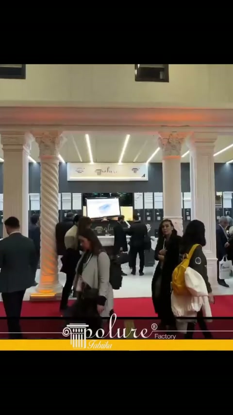 Ingresso dello stand creato con colonne dove i visitatori esaminano l'area dei prodotti
