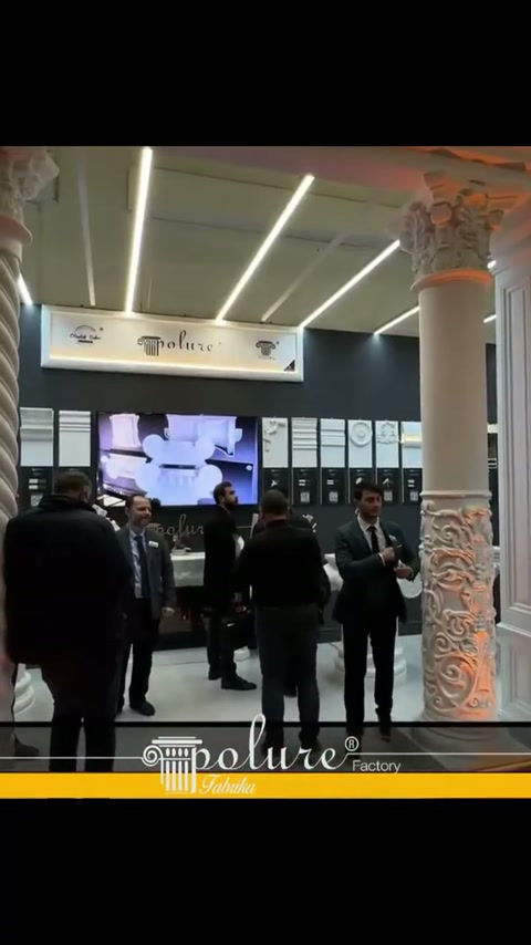 Visitatori circolano nello stand circondato da colonne classiche e scanalate
