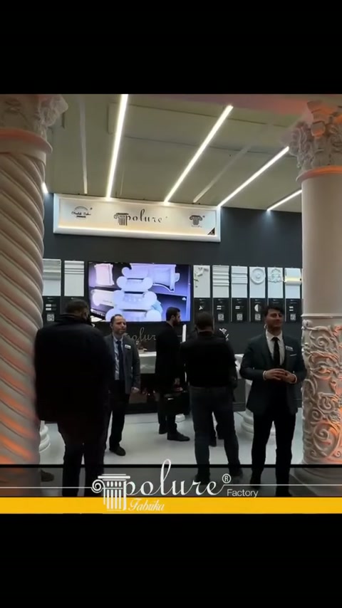 Personale dello stand e campioni murali visibili di fronte a una colonna scanalata