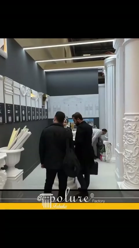 Due visitatori nel corridoio dello stand valutano la parete rivestita di profili