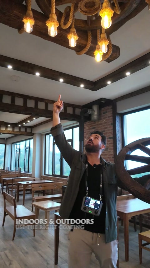 Travi effetto legno e lampade a forma di ruota di carro decorano il soffitto di un ampio ristorante.