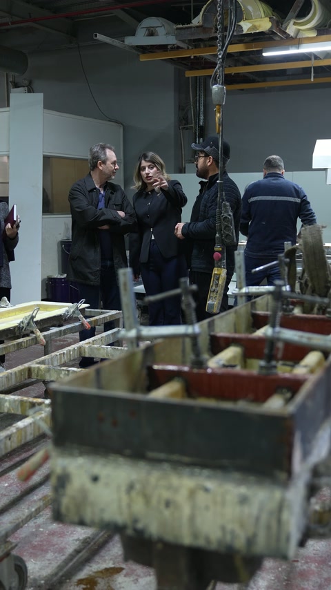 Workshop team prepares decorative components beside production equipment.