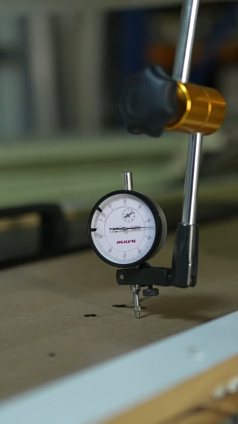 Dial gauge checks a flat component during quality control.