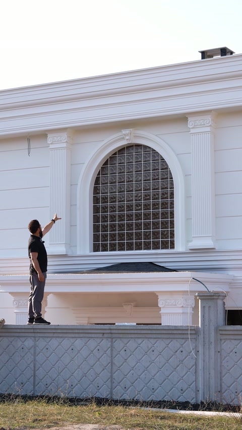 Arched window surround and horizontal mouldings define the white facade.