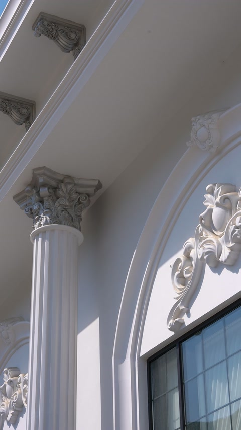Scroll-shaped window crown meets a fluted column beneath the cornice.