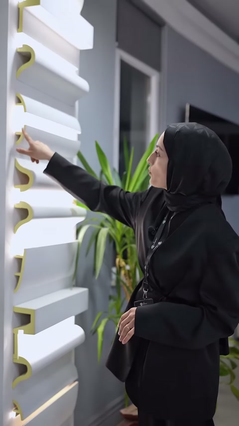 Il venditore indica il profilo di illuminazione nascosta bianco lungo sulla parete della showroom.