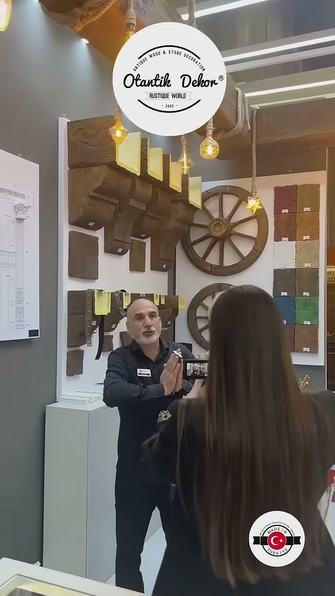 Una presentazione in uno stand organizzato con travi da soffitto, con un addetto e visitatori visibili