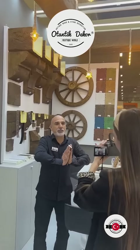 L'addetto alla presentazione spiega i prodotti davanti ai profili delle travi sulla parete, utilizzando le mani