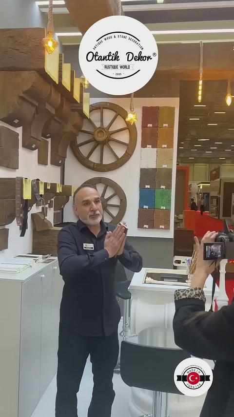 L'addetto presenta i prodotti ai visitatori in uno stand circondato da campioni di travi