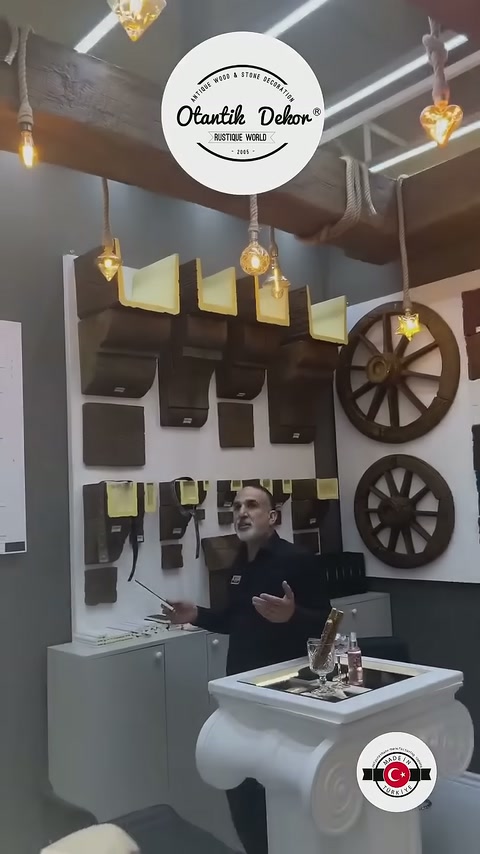 La spiegazione dei prodotti continua davanti a una parete piena di sezioni di travi decorative