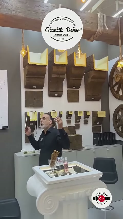 Il presentatore spiega l'uso mostrando esempi di travi in poliuretano sulla parete