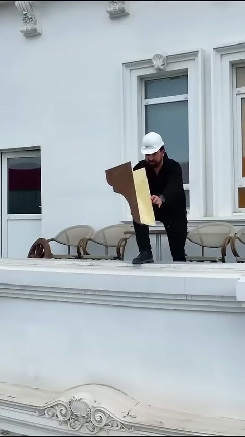 Un artigiano mostra una sezione di trave in poliuretano effetto legno su una terrazza