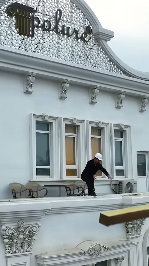 Il maestro estende un pezzo di trave dietro la ringhiera della terrazza verso il basso.