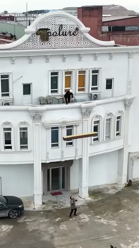 La trave in poliuretano calata dal piano superiore viene trasportata all'ingresso dell'edificio.