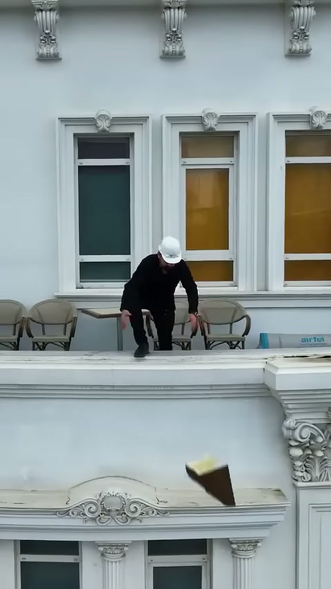 Il maestro del piano superiore cala il pezzo decorativo verso l'area di lavoro sottostante.