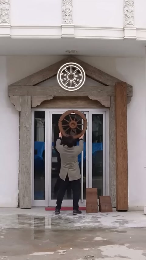 Un elemento decorativo rotondo viene posizionato al centro del timpano triangolare sopra la porta.