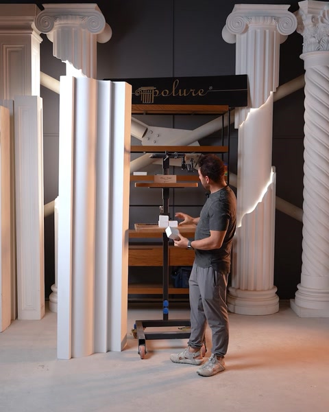 Man standing beside Corinthian pilaster columns and molding panels in workshop