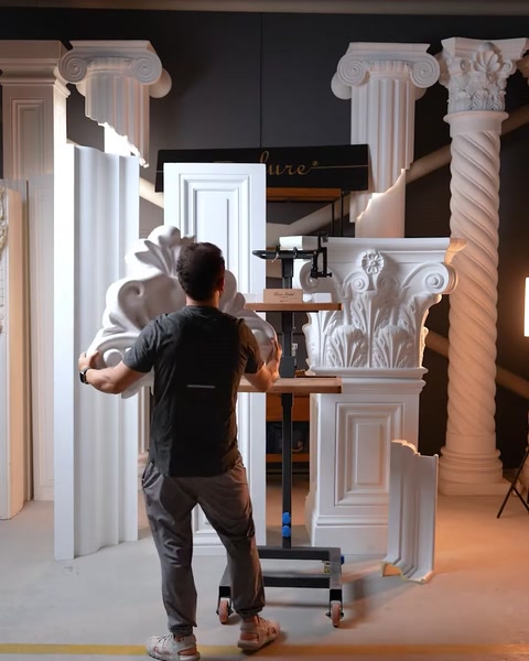 Worker arranging carved scroll applique piece near capital column