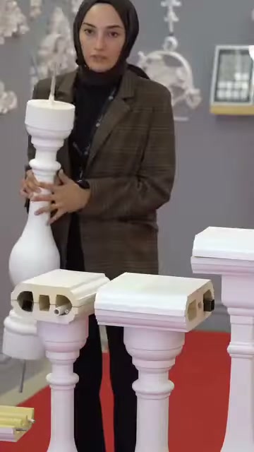 Un lungo pezzo di balaustra decorativa è tenuto verticalmente dal presentatore.
