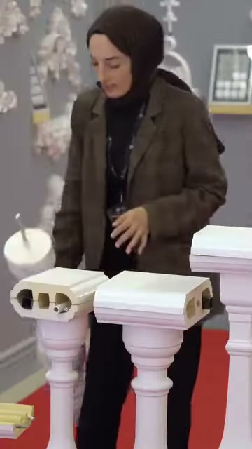 Il presentatore abbassa il pezzo di balaustra verso gli esempi di profilo sul bancone.