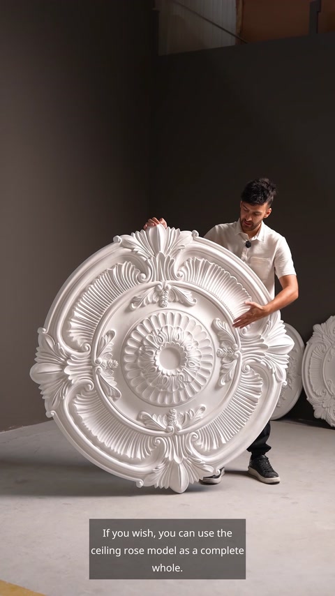 Two workers carrying large carved white ceiling medallion together