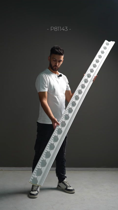 Un ampio profilo di cornice decorato con rosoni floreali viene tenuto in mano.