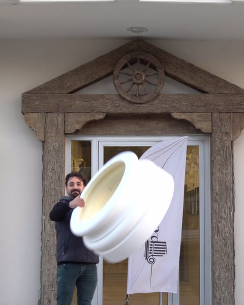 Un operaio lancia una base di colonna decorativa, dimostrandone la leggerezza.