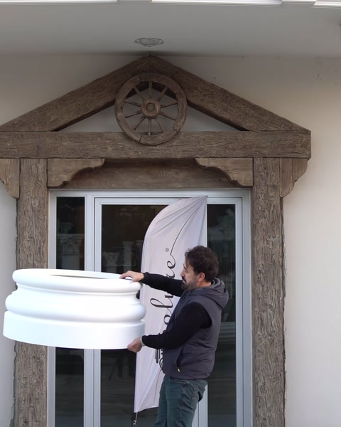 Un operaio tiene una grande base di colonna vicino a un espositore con bandiera con logo.