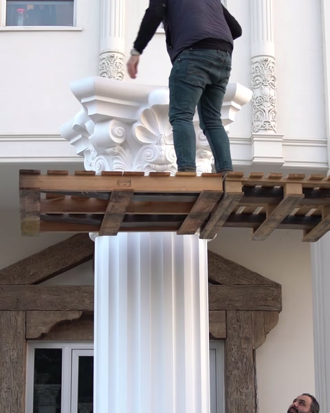 Un capitello ornato è montato sopra una colonna scanalata finita.
