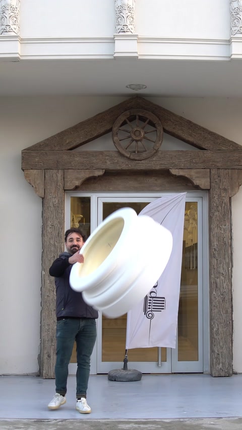 Un operaio lancia una base di colonna decorativa, dimostrandone la leggerezza.