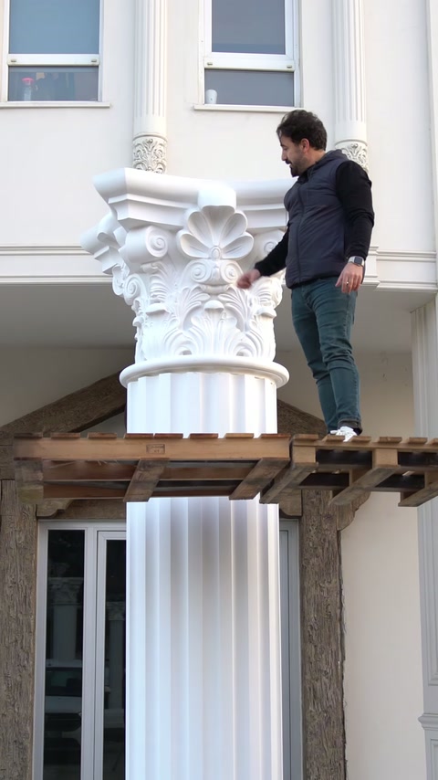 Un operaio verifica il posizionamento del capitello da una piattaforma in legno rialzata.