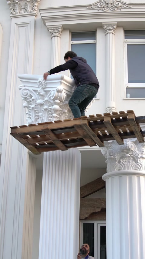 Un operaio regola un capitello ornato durante l'assemblaggio della colonna esterna.