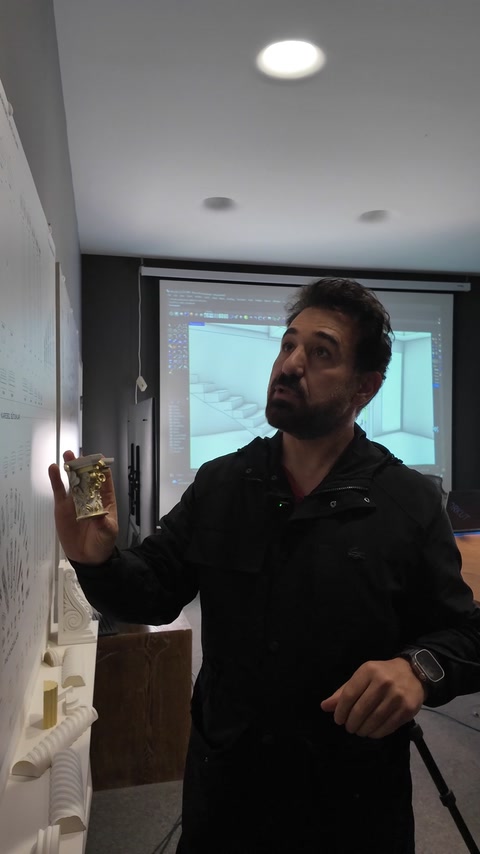 Designer holds a miniature decorative profile beside the projected model