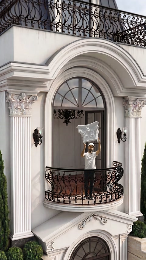 Capitello con volute esposto con entrambe le mani nell'apertura del balcone