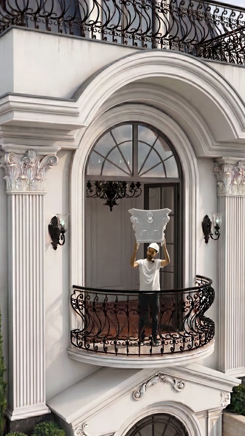 Capitello di colonna decorativa sostenuto in alto dietro la ringhiera del balcone in ferro battuto