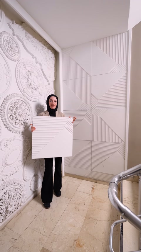 Square embossed panel held in hand in front of completed geometric wall