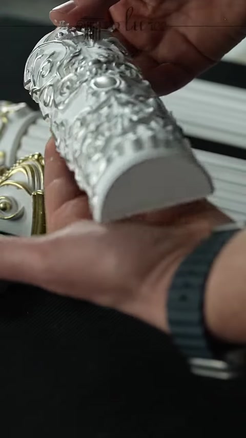 An embossed polyurethane ornament painted in a silver tone is shown in close-up