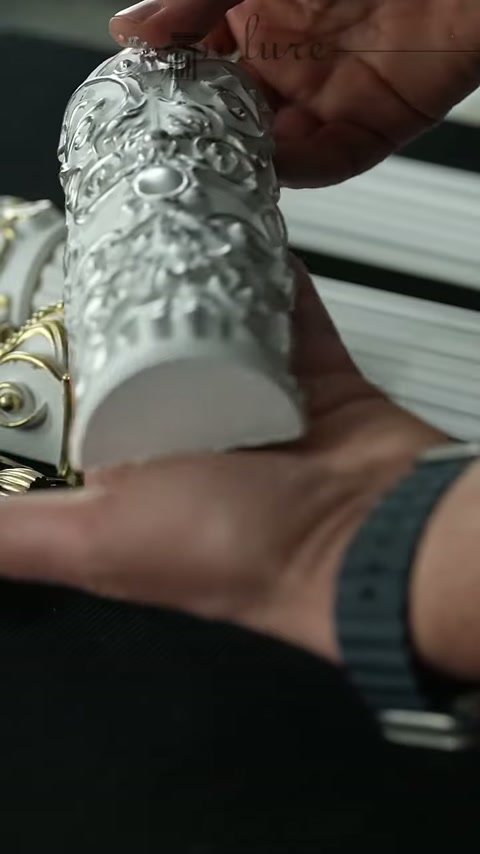 La sezione curva della decorazione in poliuretano con finitura metallizzata viene esaminata tenendola in mano