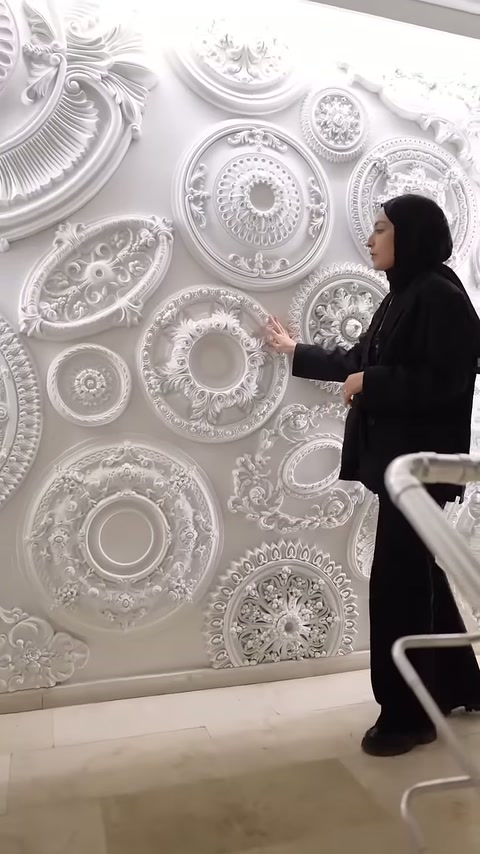 Un rosone da soffitto decorato con foglie stratificate è visibile accanto al presentatore