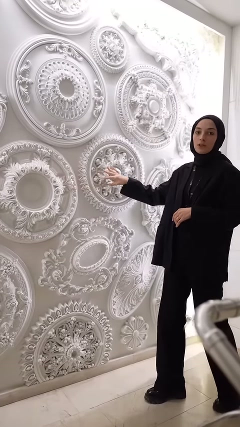Il presentatore attira l'attenzione con la mano su un piccolo ornamento da soffitto circolare densamente decorato