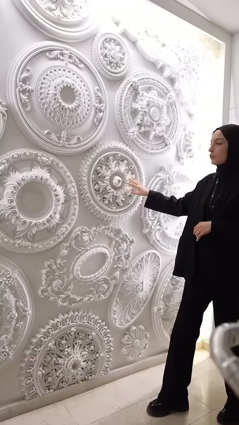 Un modello in poliuretano a forma di medaglione floreale è esaminato sulla parete dell'esposizione