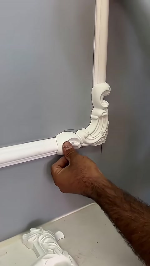 Un elemento angolare decorato viene controllato nel punto di incontro delle cornici da parete