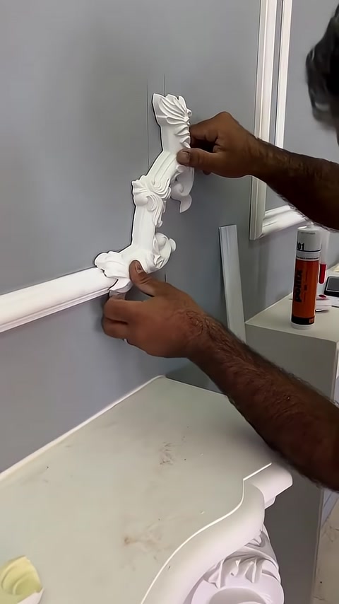Un elemento decorativo verticale viene allineato con una cornice da parete orizzontale