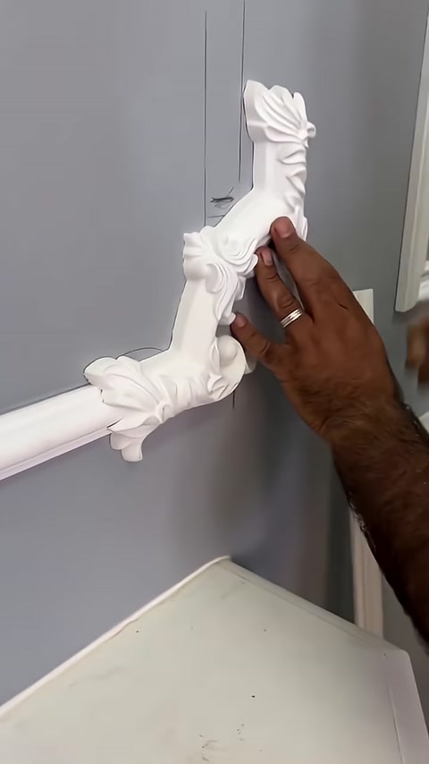 Un ornamento verticale decorato viene posizionato a mano nella composizione di cornici sulla parete